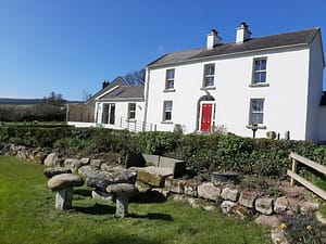 white house with a red door, front garden, stone table and bench