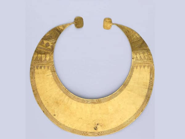 Gold lunula. Flat sheet crescent of beaten gold with quadrangular terminals. It is decorated with a finely-incised and complex geometric pattern. The horns are decorated with horizontal patterns of horizontal lines, concentric triangles, bands of diamond shaped motifs, triangles touching at their apex filled with horizontal lines, rows of small oblique lines